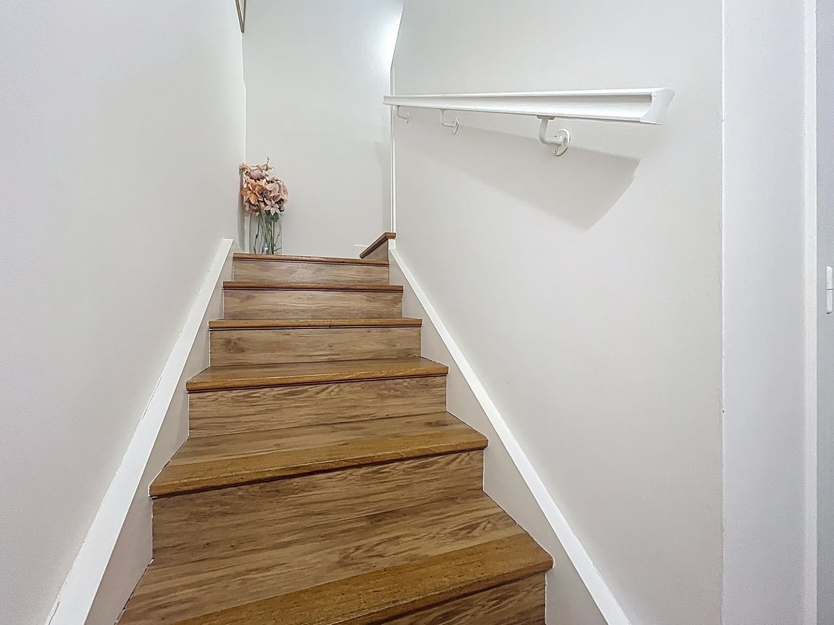 Couloir desservant les différentes pièces du duplex avec portes alignées et sol uniforme. Espace de circulation intérieur reliant les deux niveaux de l'appartement.