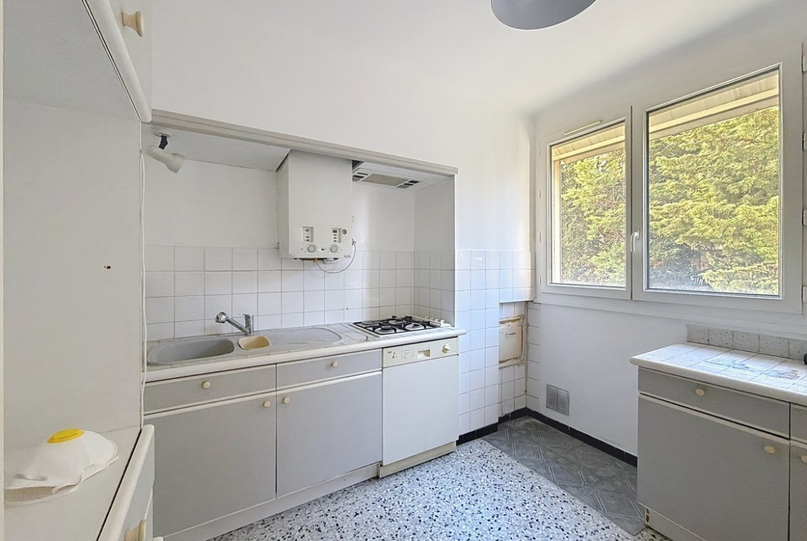 Cuisine aménagée avec meubles de rangement, plan de travail et électroménager intégré. Espace de préparation des repas avec éclairage et revêtement facile d'entretien.