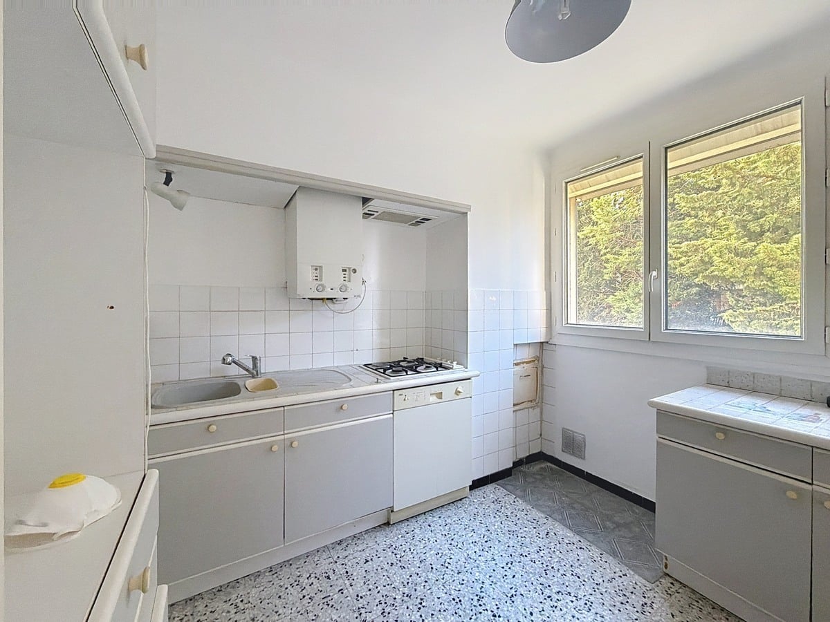 Cuisine aménagée avec meubles de rangement, plan de travail et électroménager intégré. Espace de préparation des repas avec éclairage et revêtement facile d'entretien.