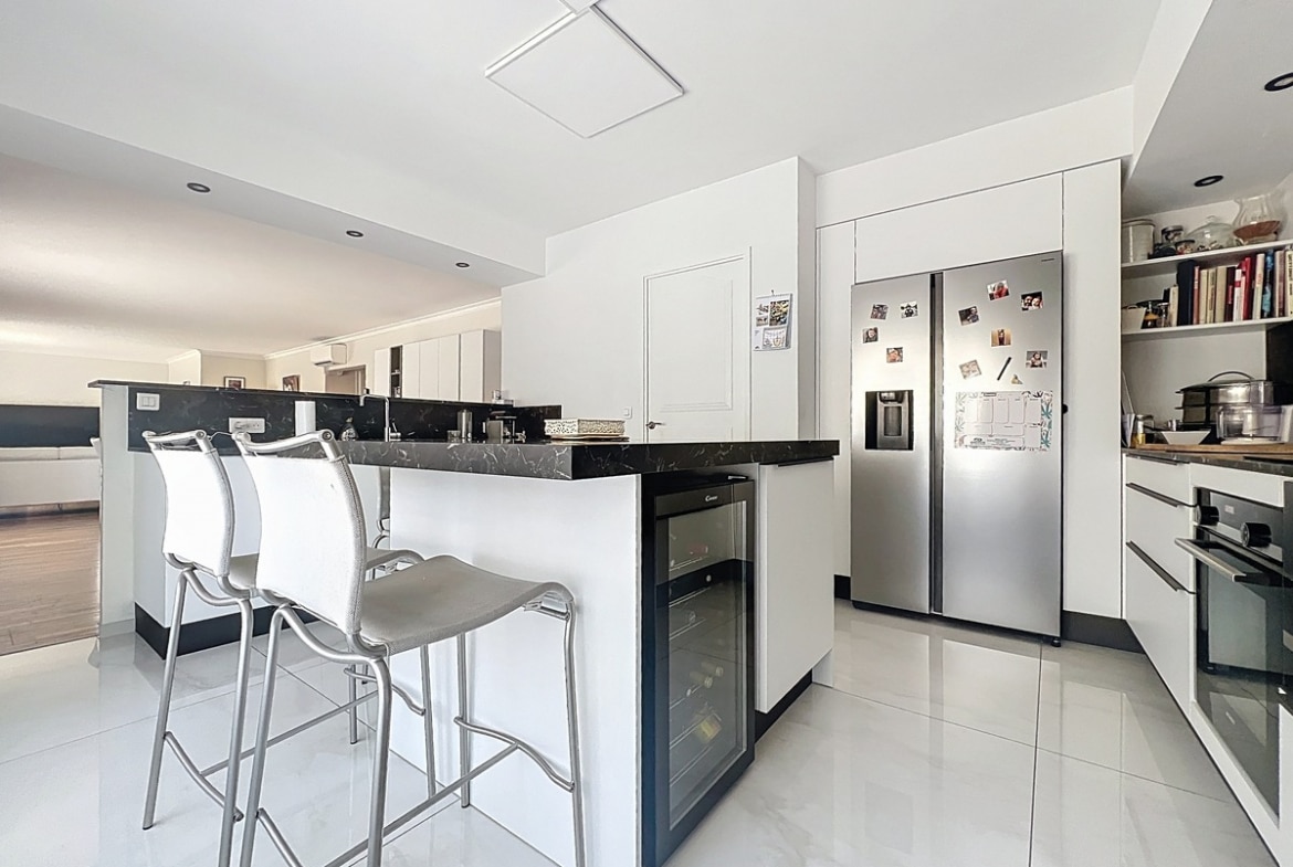 Cuisine aménagée avec meubles de rangement, plan de travail et électroménager intégré. Espace ouvert sur le séjour dans ce duplex du quartier La Balance.