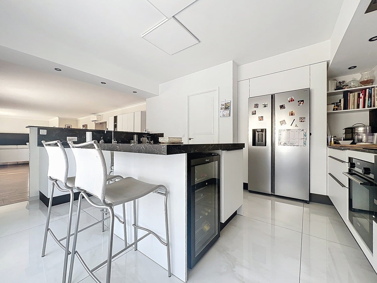 Cuisine aménagée avec meubles de rangement, plan de travail et électroménager intégré. Espace ouvert sur le séjour dans ce duplex du quartier La Balance.