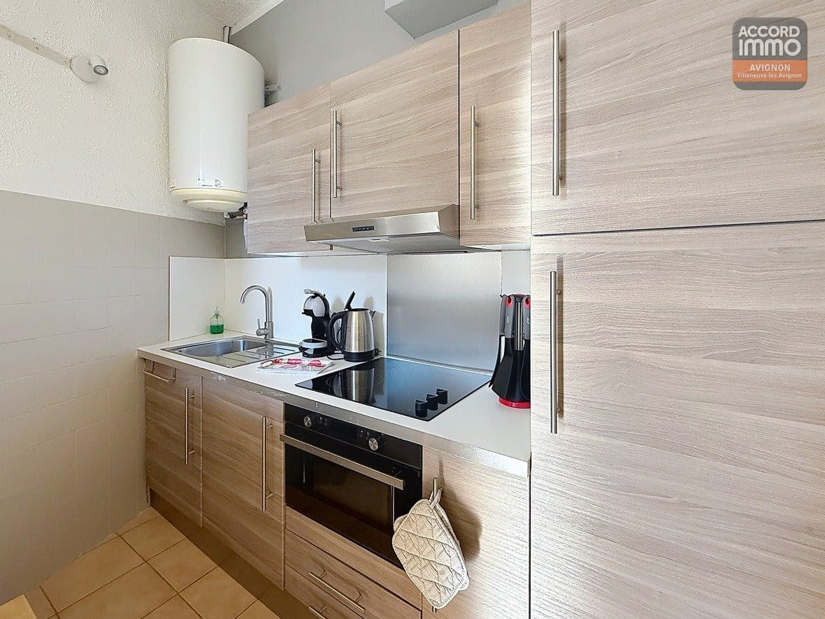 Espace cuisine avec rangements fermés, évier intégré au plan de travail et plaques de cuisson. Finitions contemporaines ou classiques, éclairage ponctuel au-dessus de la zone de préparation.