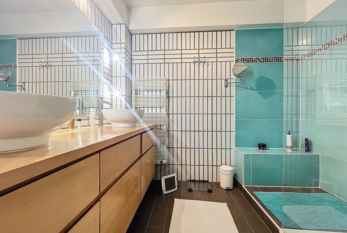 Salle d'eau avec vasque, miroir et revêtement mural carrelé. Espace sanitaire fonctionnel faisant partie des deux salles d'eau de ce duplex avignonnais.