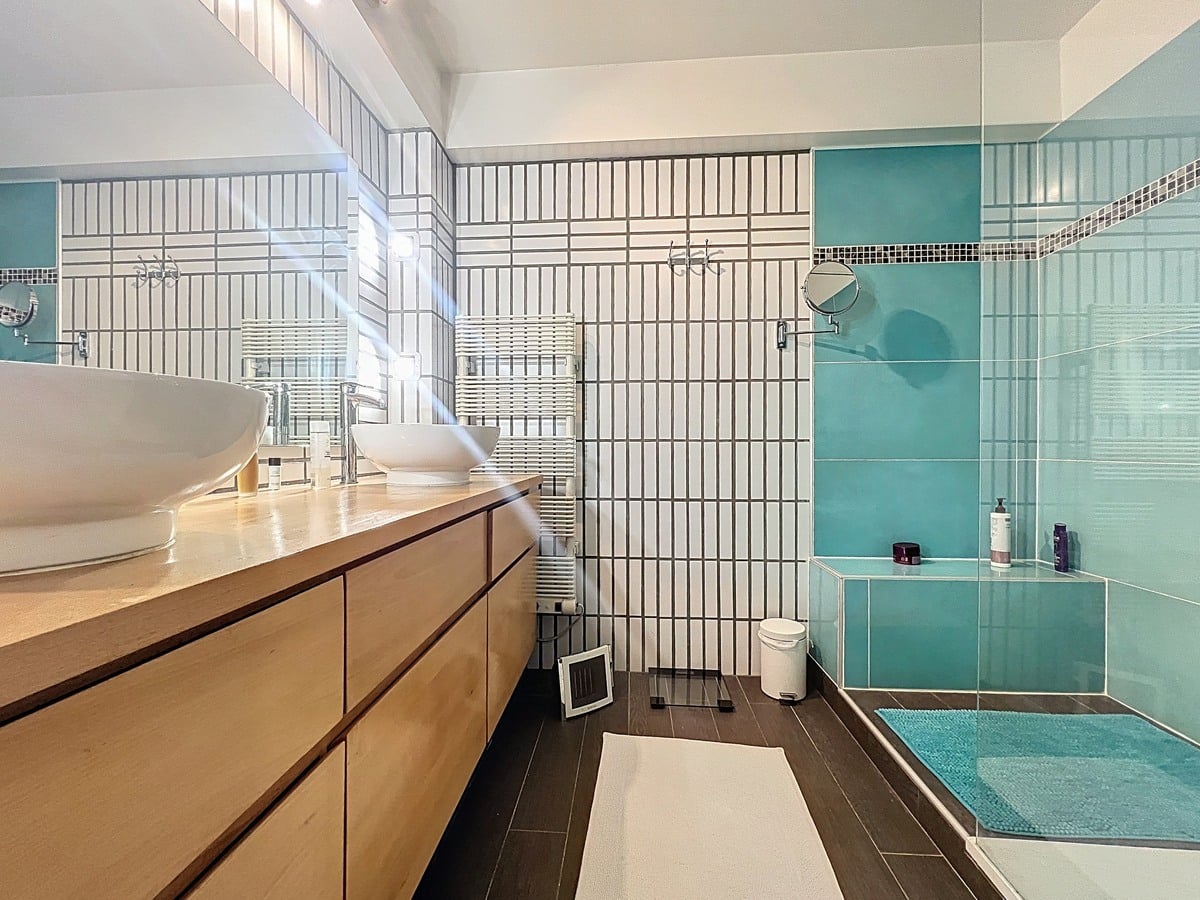 Salle d'eau avec vasque, miroir et revêtement mural carrelé. Espace sanitaire fonctionnel faisant partie des deux salles d'eau de ce duplex avignonnais.