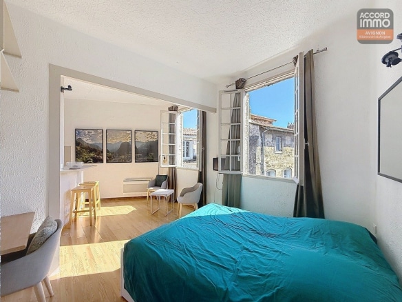 Séjour orienté sud avec fenêtre à huisserie bois, sol en carrelage ou parquet et murs clairs. Espace polyvalent accueillant coin salon et zone repas, hauteur sous plafond standard.