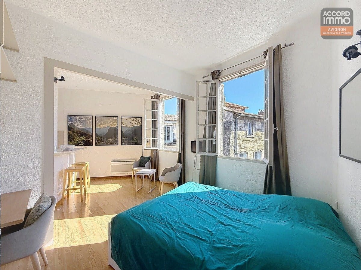 Séjour orienté sud avec fenêtre à huisserie bois, sol en carrelage ou parquet et murs clairs. Espace polyvalent accueillant coin salon et zone repas, hauteur sous plafond standard.