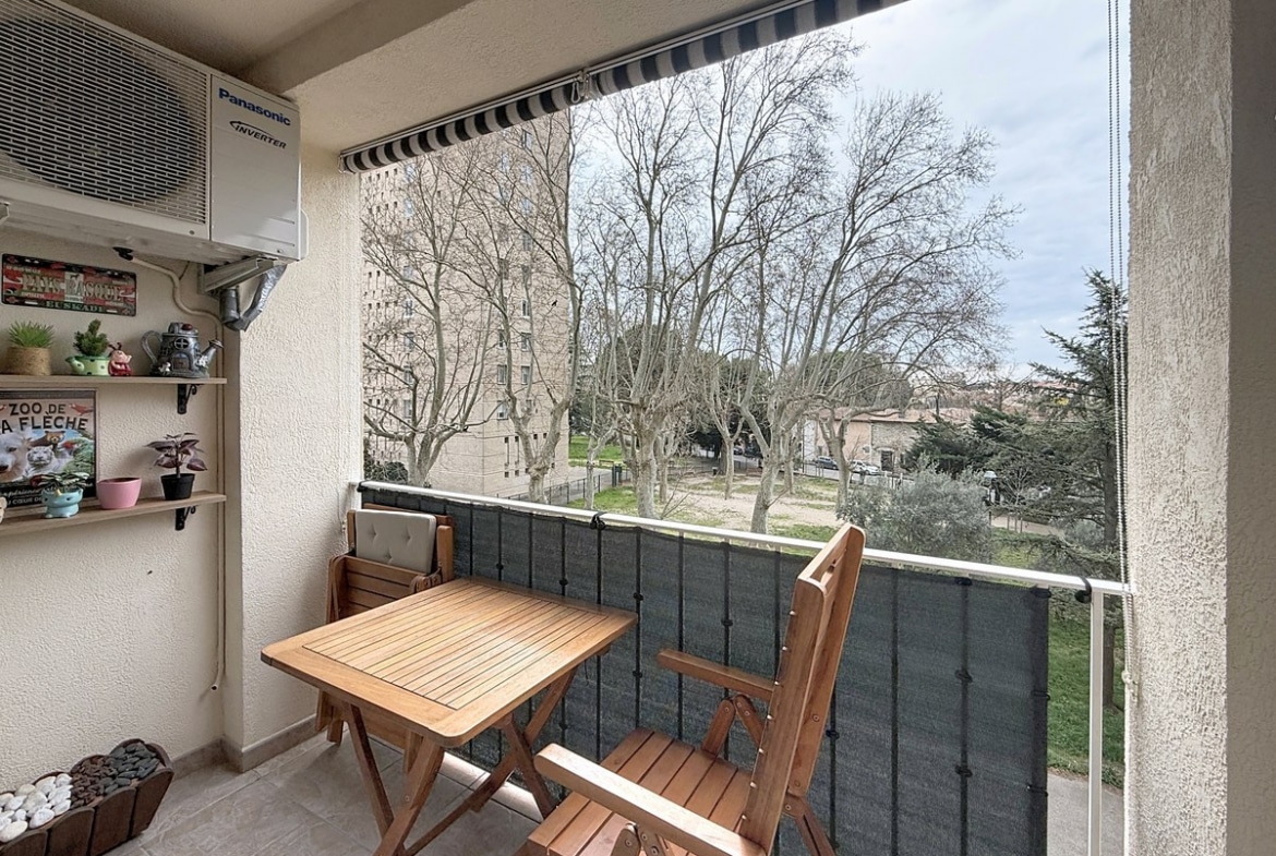accès direct au balcon par porte-fenêtre qui a une table et des chaises en bois et des étageres au mur