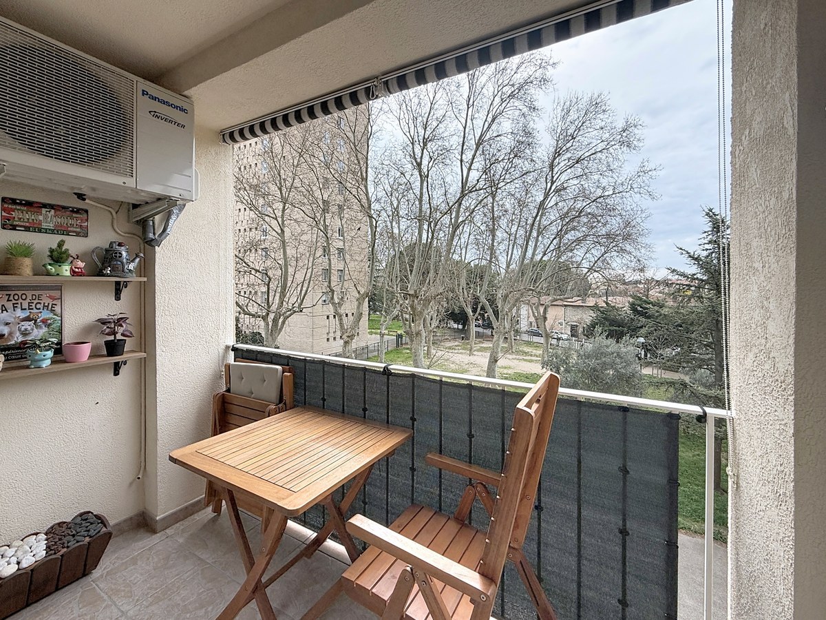 accès direct au balcon par porte-fenêtre qui a une table et des chaises en bois et des étageres au mur