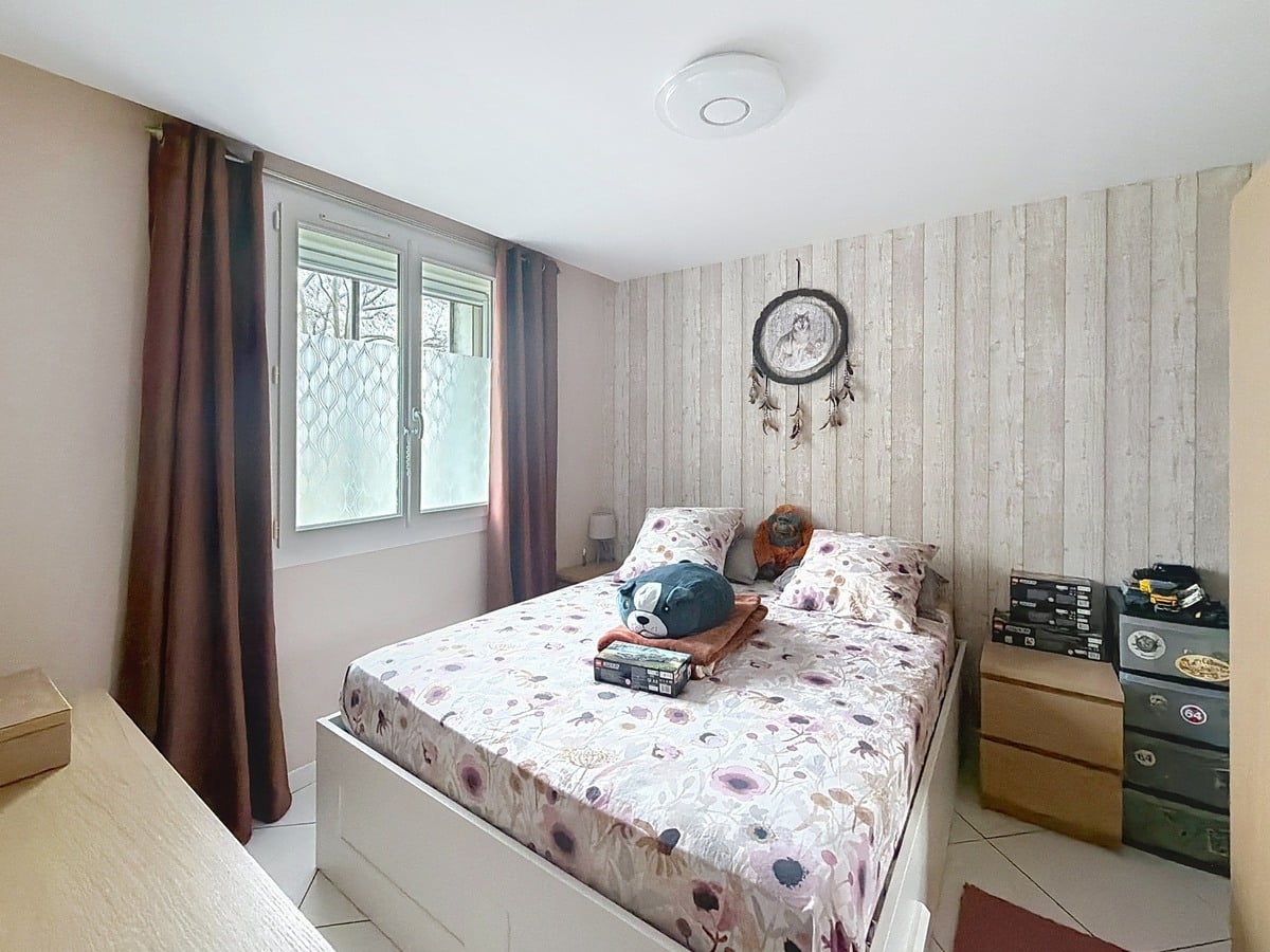 Chambre avec murs clairs et fenêtre apportant la lumière naturelle. Espace aménageable avec placard de rangement intégré.