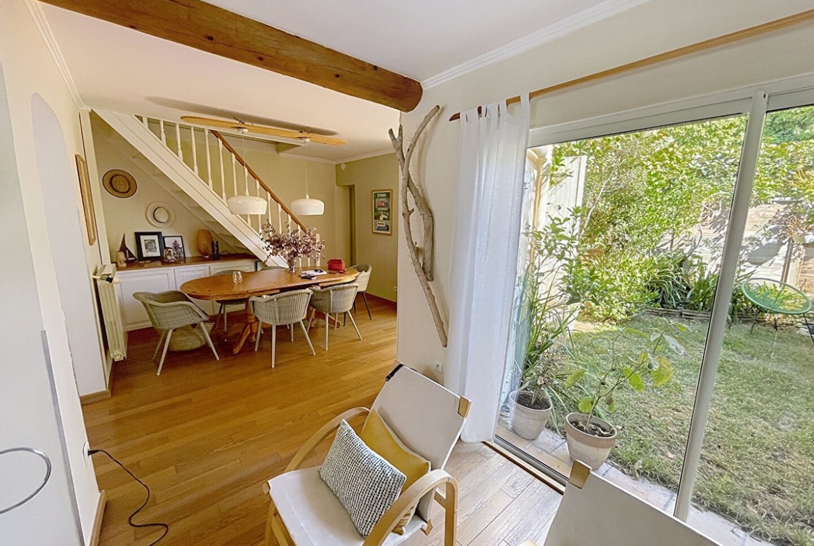 Séjour donnant sur une salle à manger avec table ovale en bois, chaises en rotin, escalier blanc et parquet clair dans une maison en vente à Avignon
