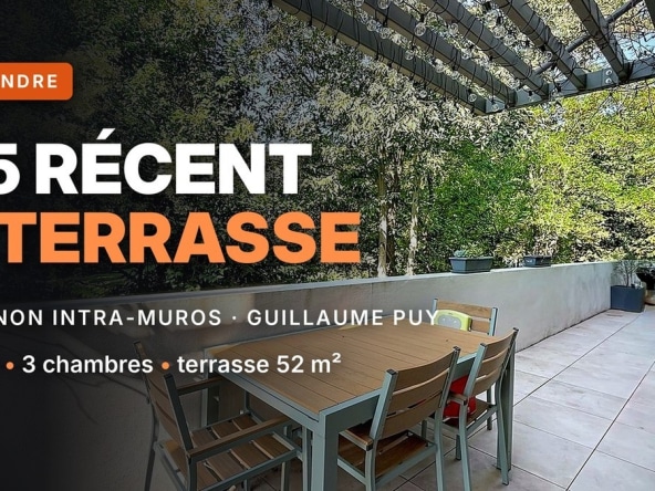 Terrasse dallée de carrelage gris clair équipée d'une table et chaises de jardin en aluminium gris et bois, couverte d'une pergola métallique noire avec guirlande lumineuse. La terrasse est bordée d'un muret blanc bas et donne sur une végétation dense d'arbres à feuilles vertes en arrière-plan.